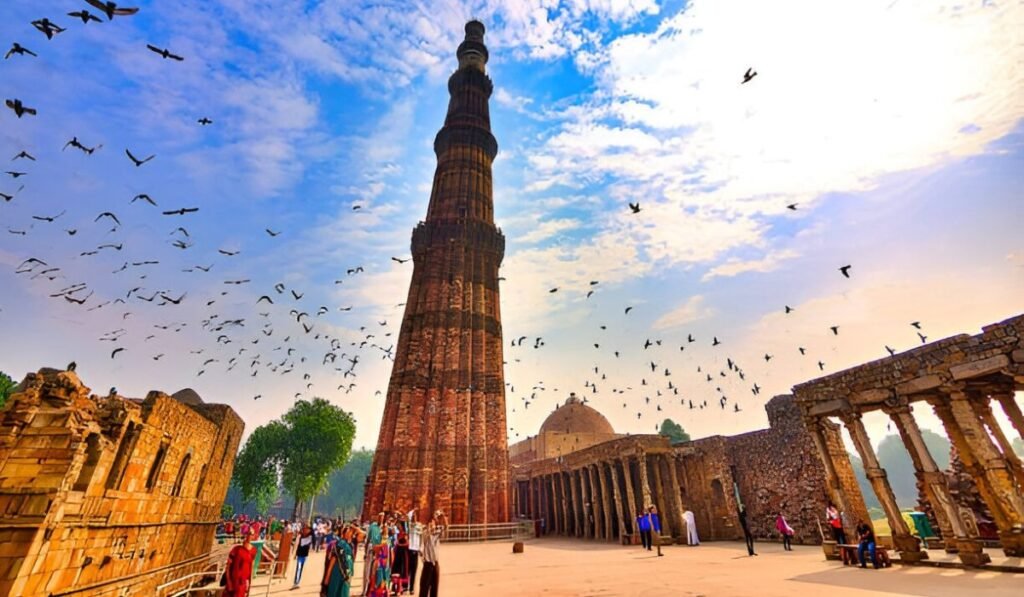 The Story Is Bigger Than the Tower – Qutub Minar History Qutub Minar surrounded by historic ruins and flying birds at a heritage site in Delhi